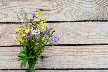 Bouquet of field flowers on a wooden background.