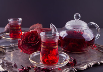 Cups of hot red karkade tea with teapot on the tray