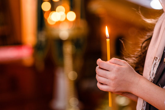 Close up children's hands hold a candle in the church in prayer. Empty space for text