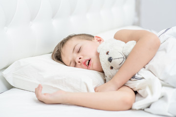 Young boy with toy bear is sleeping with his mouth open, snoring