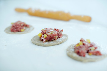 The girl carefully and gently sculpts meat pies. hands closeup on the table with flour