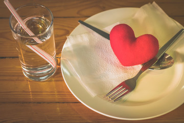 A little heart pillow on a dish with fork and spoon on table in .restaurant