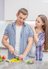 Happy family at kitchen. Young couple cooking together at home