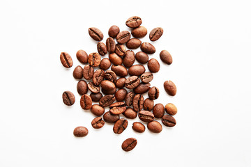 Roasted brown coffee beans scattered on white table with a lot copy space for text. Flat lay composition. Close up, top view, background.