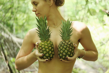 Blond girl posing for photo at forest with pineapple