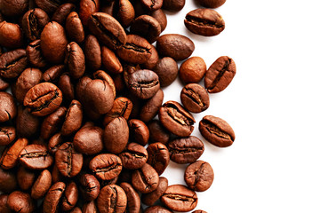 Roasted brown coffee beans scattered on white table with a lot copy space for text. Flat lay composition. Close up, top view, background.