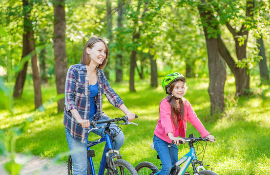 Happy Sporty Family. Mom And Daughter Are Cycling In The Park Together