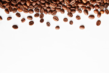 Roasted brown coffee beans scattered on white table with a lot copy space for text. Flat lay composition. Close up, top view, background.