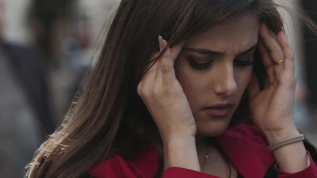 Pretty woman tolerates headache, looks at camera and at the sky