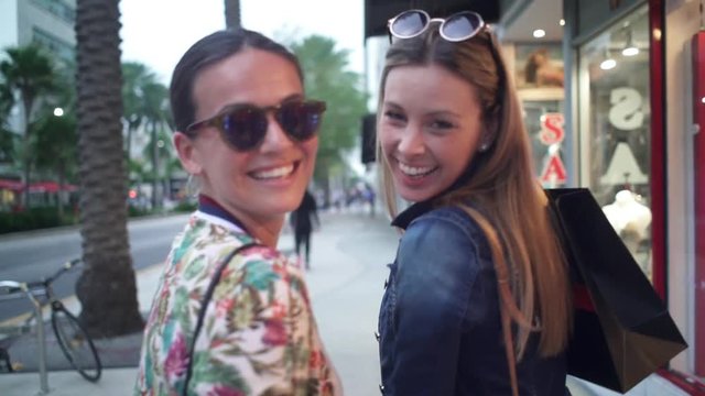 Slow motion of best friends smiling at camera on shopping trip