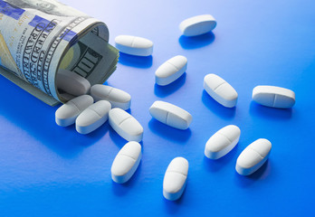 A medical pills in rolled 100 US dollar banknotes. Symbolic image of high medical expenses or drug dealing, dealer or trade. 