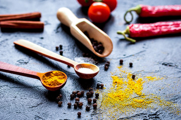 spices in wooden spoon on dark background