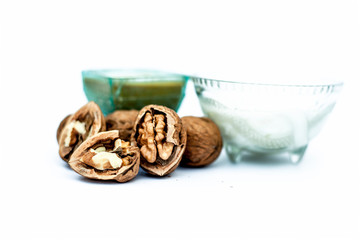 Close up of walnut face pack to prevent hair damage isolated on white i.e. walnut powder well mixed with curd in a glass bowl with entire raw ingredients.