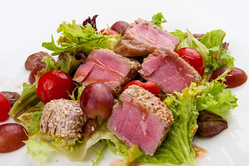 Salad with fried tuna, tomatoes and chestnuts, on a white background