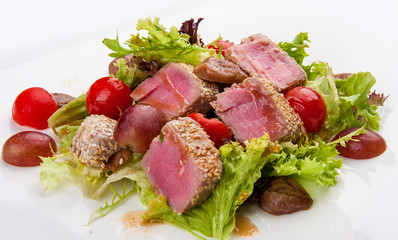 Salad with fried tuna, tomatoes and chestnuts, on a white background