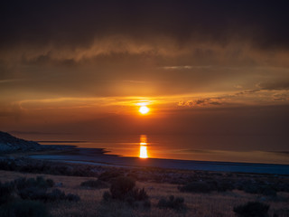 Obraz premium Sunset on the Antelope Island on the great Salt Lake outside the City, colorful orange dusk above a road with buffalos panorama background