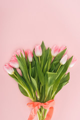 top view of spring floral bouquet with tulips and ribbon isolated on pink