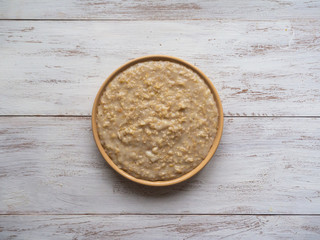 Oatmeal in a plate on a white wooden table.