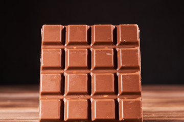 Milk chocolate bar on wooden background, macro photo