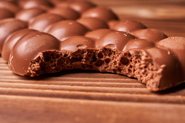 Bitten milk chocolate bar on wooden background