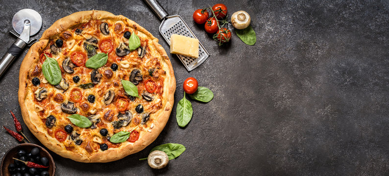 pizza with tomatoes, cheese, mushrooms, olives and spinach on a dark background