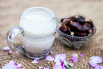 Close up shot of popular Indian & Asian Khajor dudh or dates milk in a transparent glass bowl along with raw dates on a brown colored surface or background.