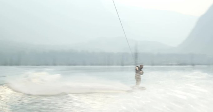 Front view of caucasian young man doing tricks on wakeboard in the city river 4k