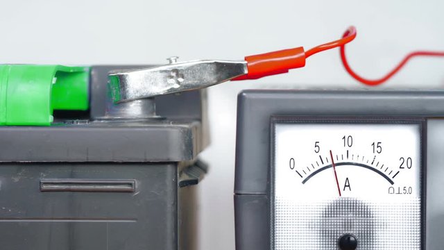 The car battery is powered by a charger with an ammeter.