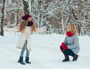 Mother and child girl on a winter walk in nature. Young family enjoying a day out playing in the winter forest