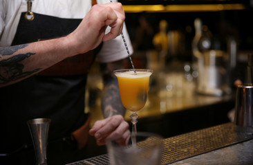 Bartender preparing tasty cocktail at counter in nightclub, closeup