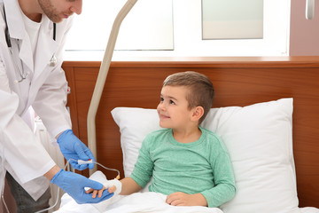 Doctor adjusting intravenous drip for little child in hospital