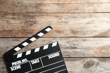 Clapperboard on wooden background, top view with space for text. Cinema production