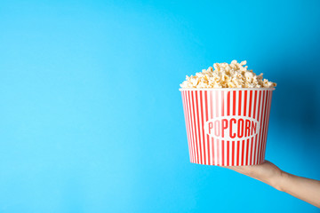 Woman holding popcorn bucket on color background, closeup with space for text. Cinema snack