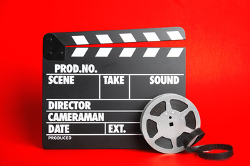 Clapperboard and reel on color background. Cinema production