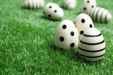 Traditional Easter eggs decorated with black paint on green lawn, space for text