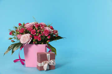 Beautiful bouquet of flowers and gift box on color background. Space for text