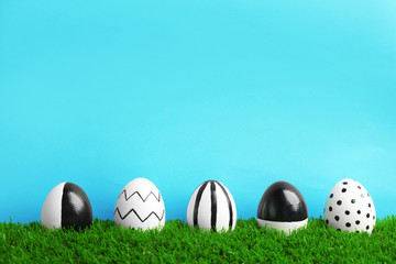 Line of painted Easter eggs on green lawn against color background, space for text