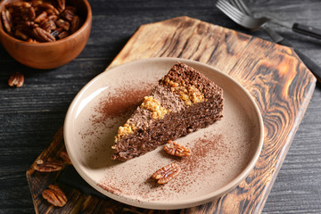 Plate with piece of tasty chocolate cake with pecan nuts on table