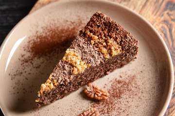 Plate with piece of tasty chocolate cake with pecan nuts, closeup