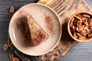 Plate with piece of tasty chocolate cake with pecan nuts on table