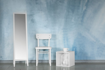 Mirror, chair and stand near color wall
