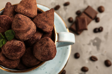 Cup with tasty sweet truffles on grey table, closeup