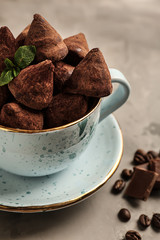 Cup with tasty sweet truffles on grey table, closeup