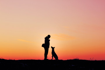 Fototapeta na wymiar Silhouettes of man and dog on sunset background