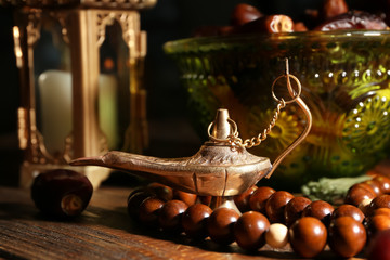 Aladdin lamp of wishes, tasbih and dates on wooden table