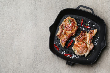 Grill pan with tasty cooked meat and spices on grey background