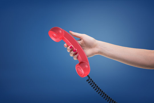 A Female Hand With Painted Nails Holds A Red Retro Phone Receiver With A Black Cord.