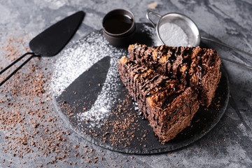 Slate plate with pieces of tasty chocolate cake on grey table