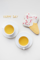 two cups of coffee on a table with cookies