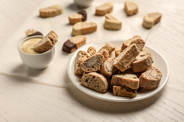 Plate with tasty Italian biscotti and sauce on light table